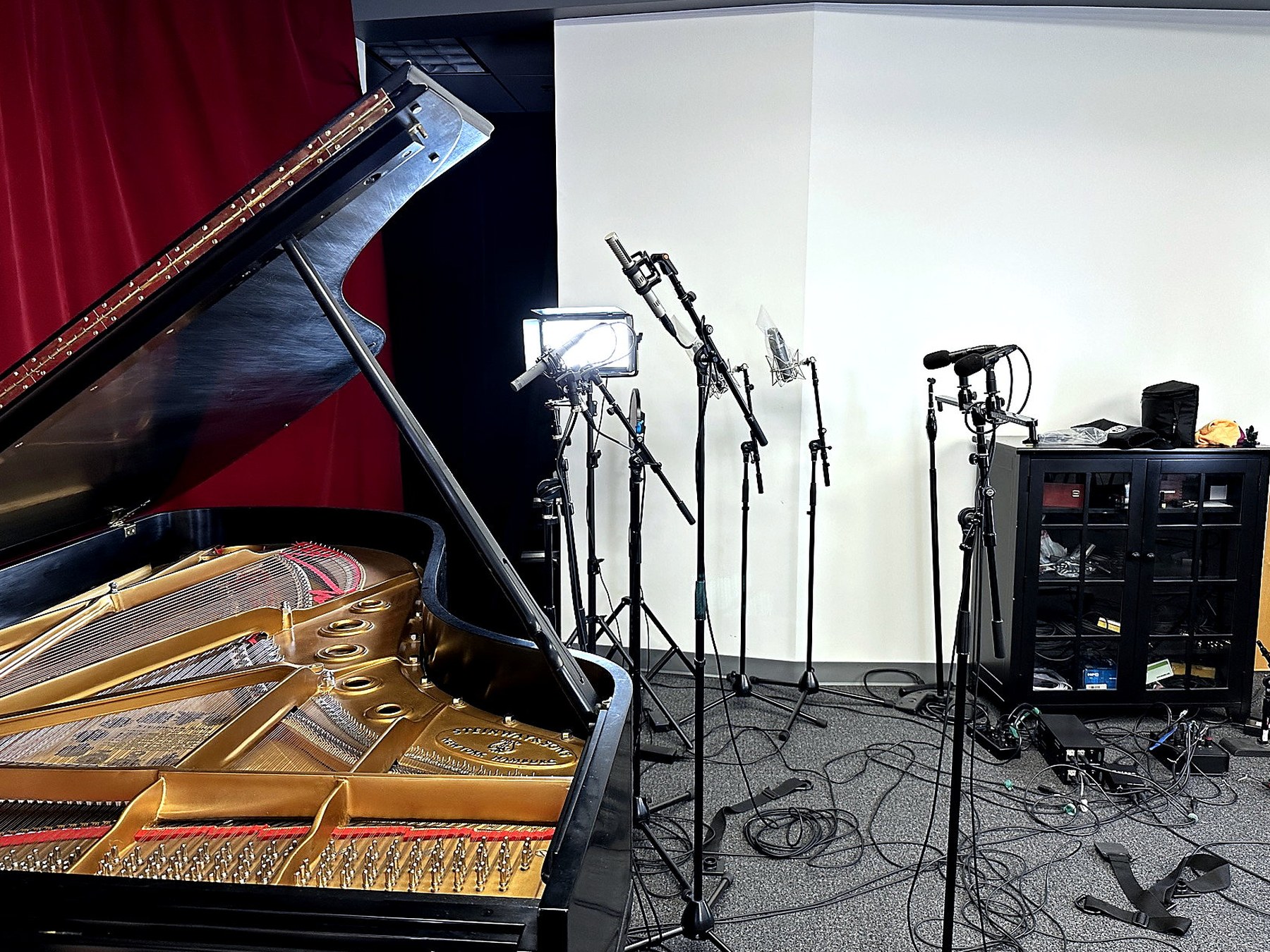Open Steinway grand piano with microphone stands and recording rack