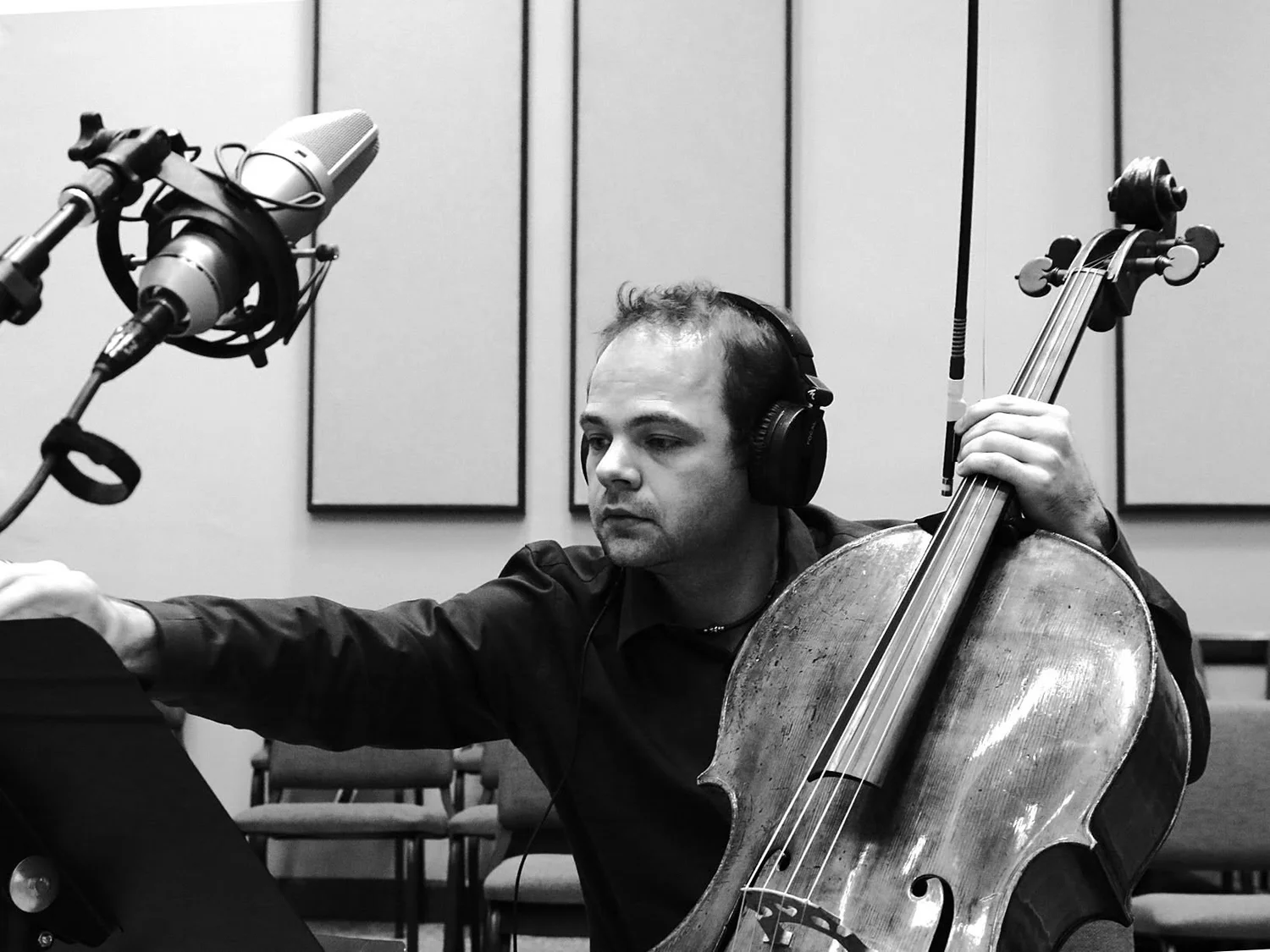 Laszlo Mezo adjusting a studio setup with cello and microphone
